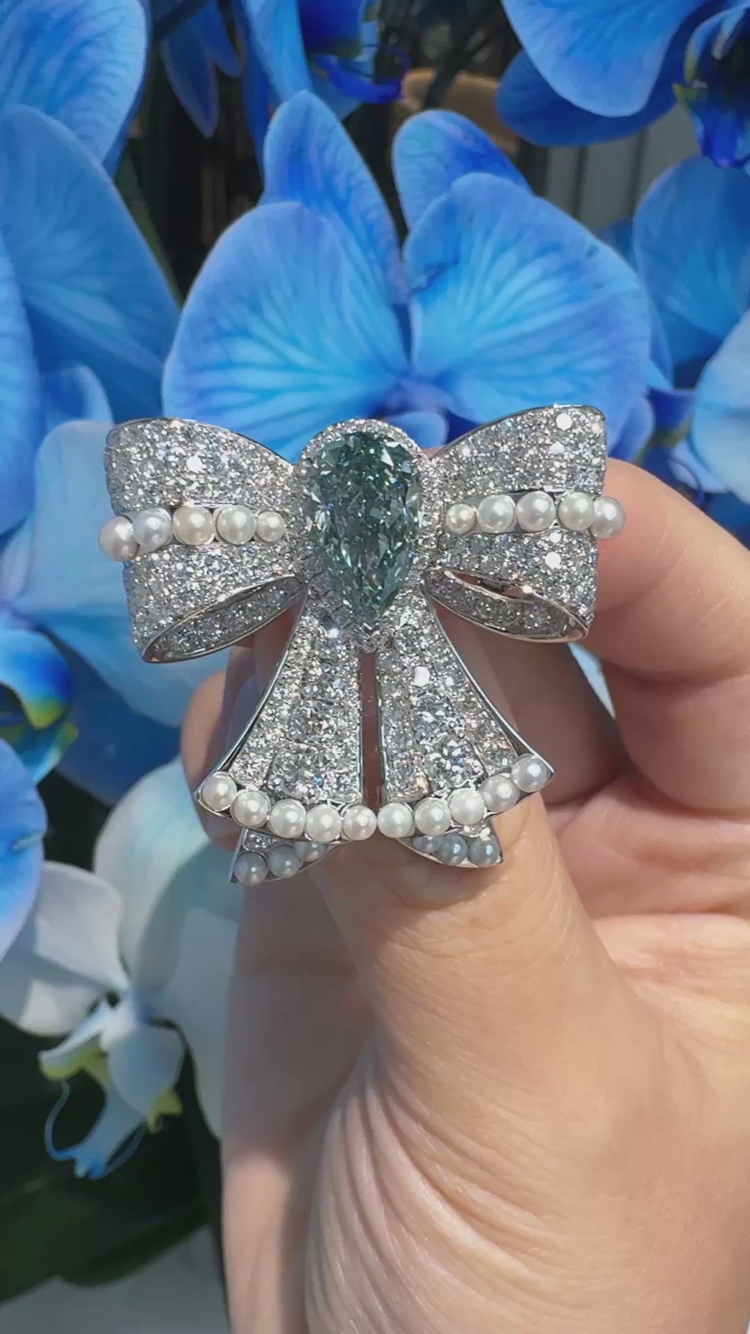 18K gold bow-shaped aquamarine brooch with pearl and diamond centerpiece.